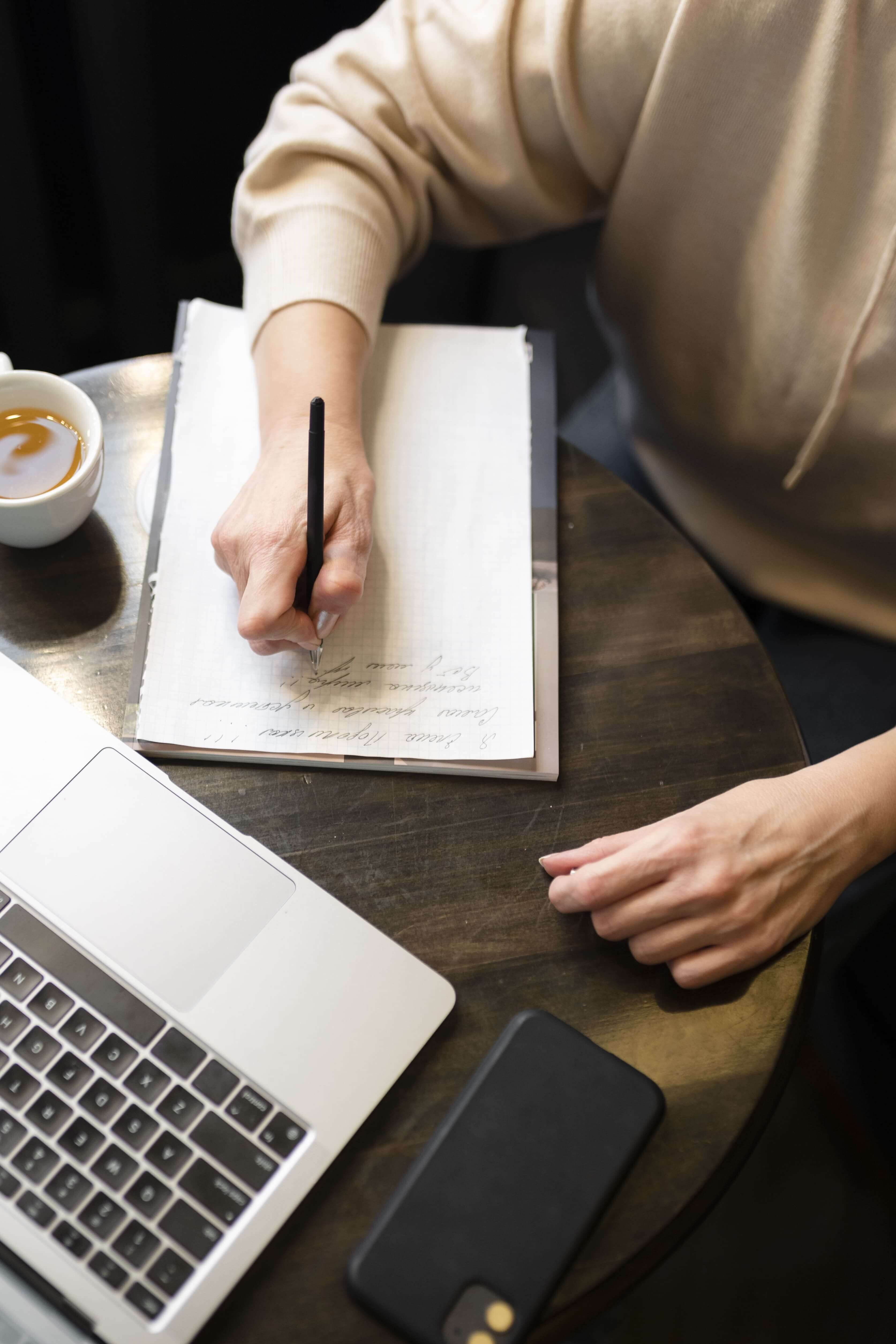 elderly woman drinking coffee cafe while working her laptop writing her notebook